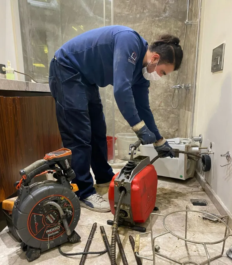 Banyo giderinde spiral makineyle çalışan teknisyen