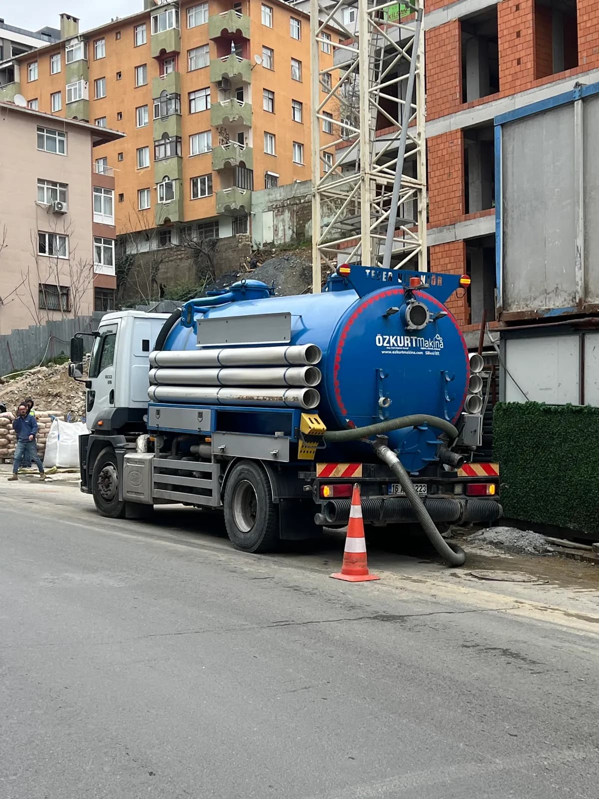 Sokakta hortumlarla çalışan mavi vidanjör aracı